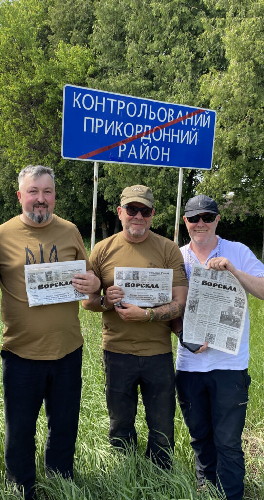 Волонтери з Великої Британії та редактор «Ворскли» з газетою біля знака контрольованого прикордонного району на Сумщині