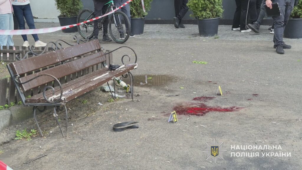 Місце вибуху гранати в Охтирці біля закладу харчування: лавка, сліди крові та огороджена поліцією територія після інциденту, внаслідок якого постраждали люди.