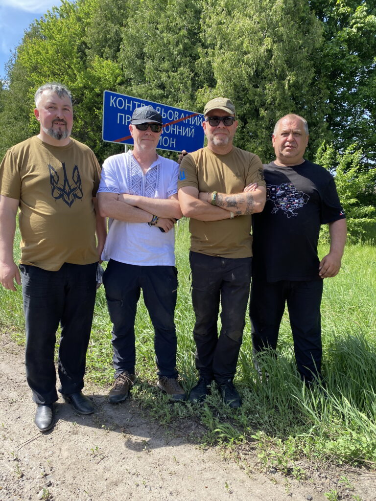 Волонтери з Великої Британії та редактор «Ворскли» з газетою біля знака контрольованого прикордонного району на Сумщині