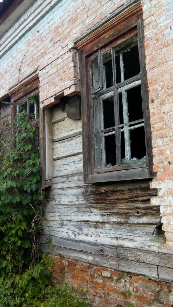 Стара будівля в Охтирці на провулку Якова Майтюренка, 19: вибиті вікна, дерев’яні стіни під цегляною кладкою та заросле подвір’я.