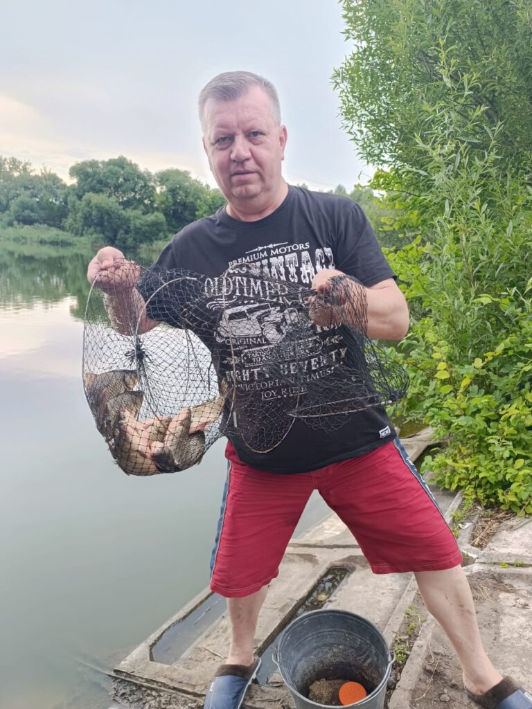 Віталій Кохан тримає садок із рибою після риболовлі біля водойми.